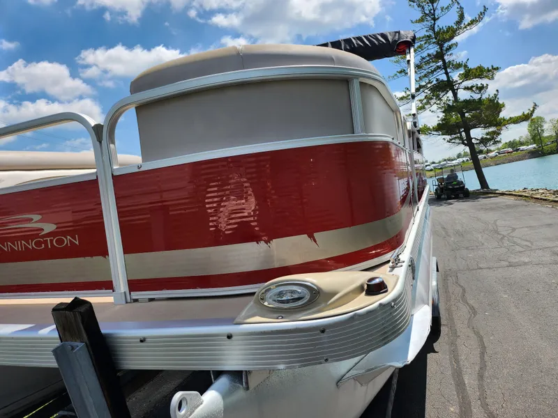 Slide: The Image of 2012 Bennington 22 SSL pontoon boat with red and beige exterior, parked near a lake. - 6
