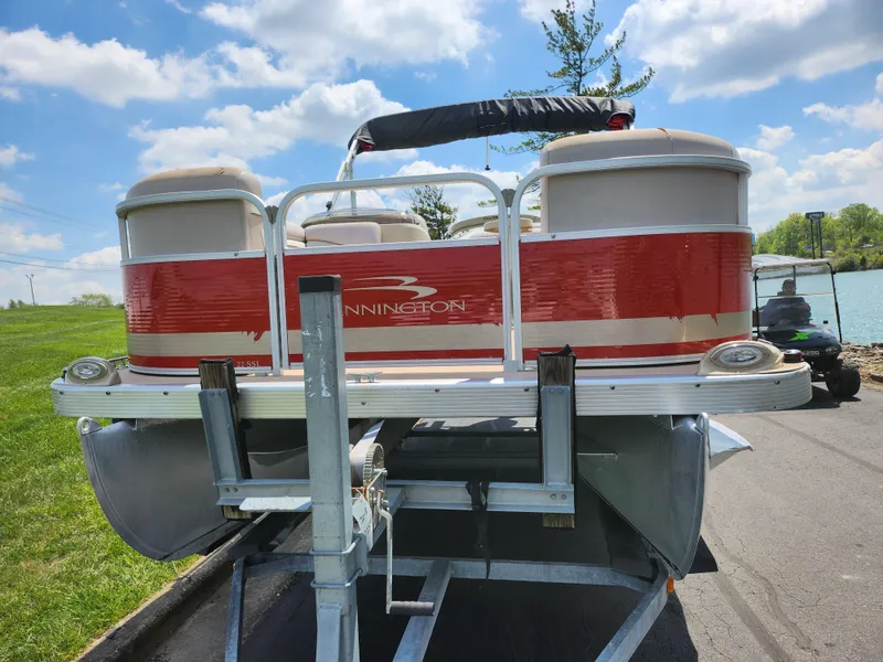 Slide: The Image of 2012 Bennington 22 SSL pontoon boat on trailer, red and white design, parked near a lake. - 7