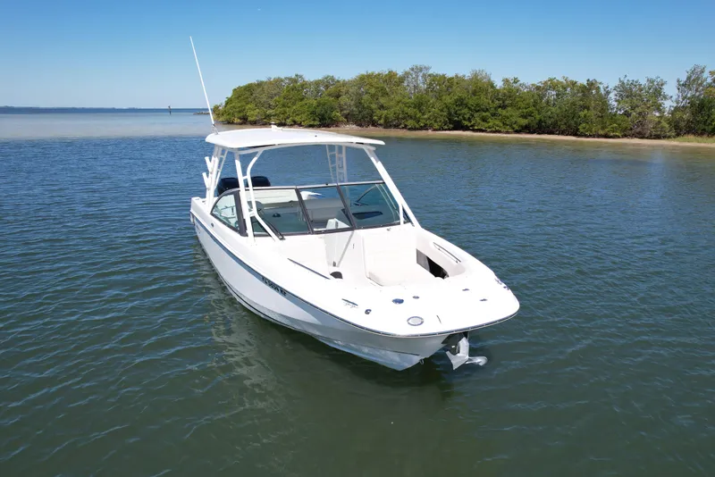 Slide: The Image of 2017 Boston Whaler 270 Vantage boat on calm water near a lush shoreline. - 12