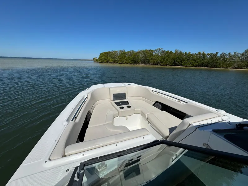 Slide: The Image of 2017 Boston Whaler 270 Vantage boat on calm water near a lush shoreline. - 16