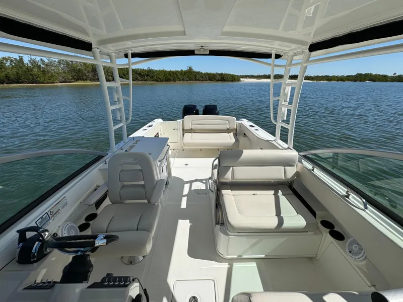 Slide: The Image of 2017 Boston Whaler 270 Vantage boat interior on calm water, featuring seating and helm. - 21