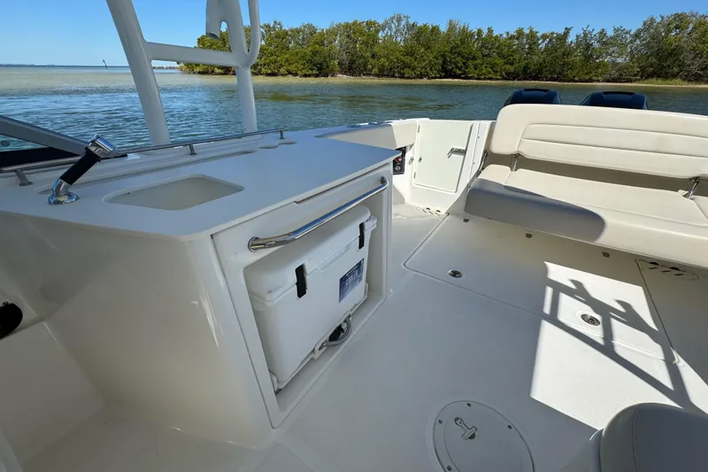 Slide: The Image of 2017 Boston Whaler 270 Vantage interior with seating and storage, near water and trees. - 26