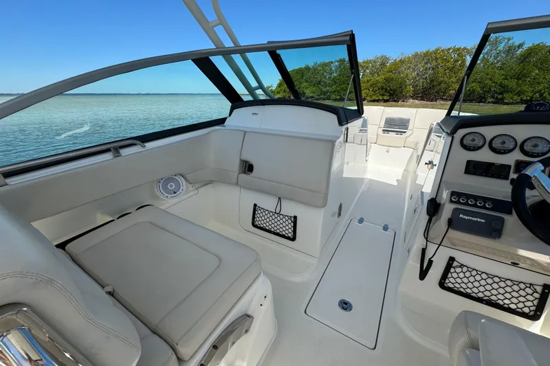 Slide: The Image of 2017 Boston Whaler 270 Vantage interior with seating and dashboard, near water and trees. - 28