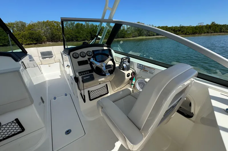 Slide: The Image of 2017 Boston Whaler 270 Vantage boat interior with steering wheel and seating, near water. - 29