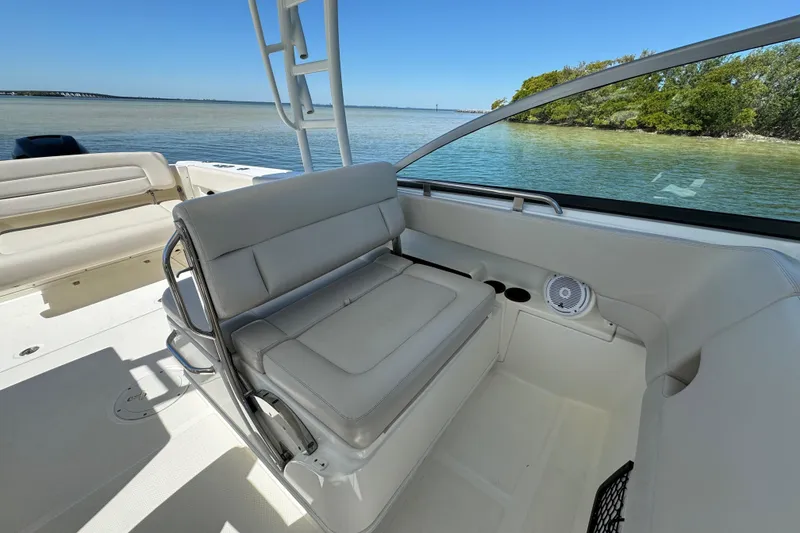 Slide: The Image of 2017 Boston Whaler 270 Vantage boat interior with seating, near calm waters and greenery. - 30