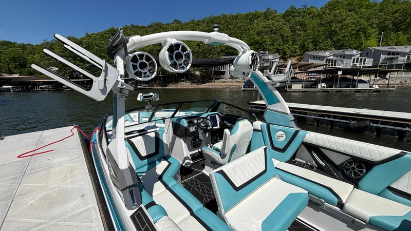 Slide: The Image of 2019 Tigé 25 ZXS boat with teal and white interior, docked by a lake. - 14