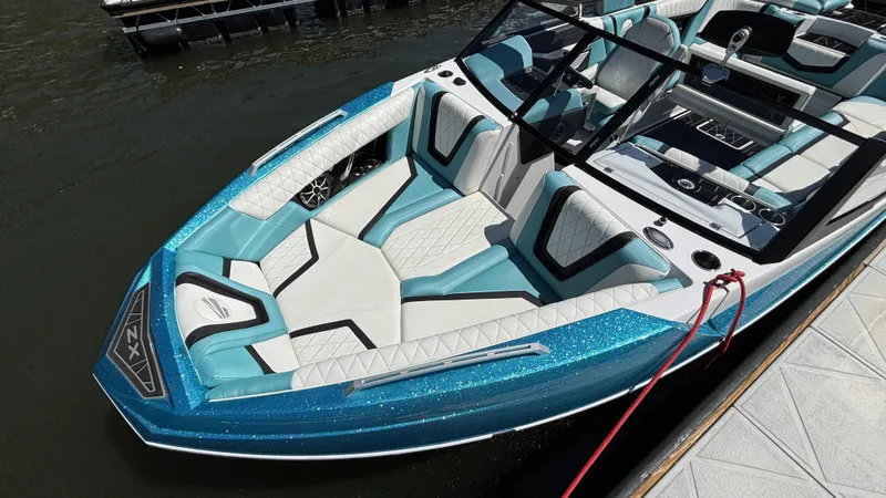 Slide: The Image of 2019 Tigé 25 ZXS boat with blue and white interior, docked on water. - 16