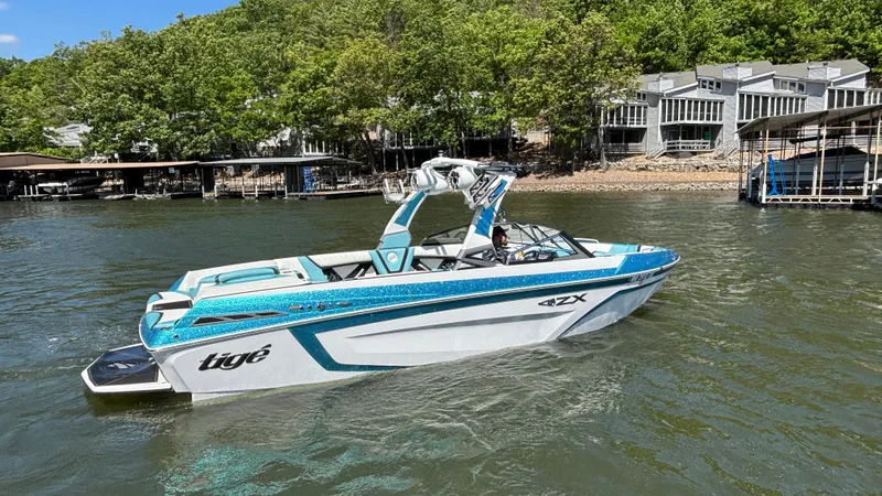 Slide: The Image of 2019 Tigé 25 ZXS boat on a lake with modern houses in the background. - 3