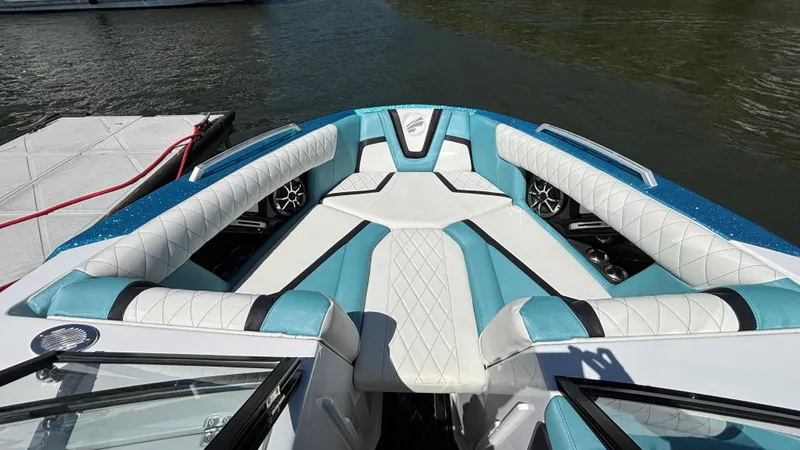 Slide: The Image of 2019 Tigé 25 ZXS boat interior with white and teal seating, docked by the water. - 31