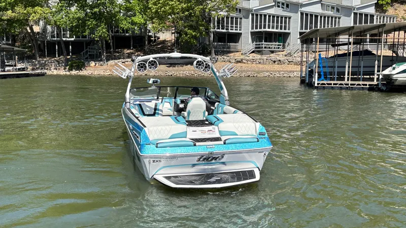 Slide: The Image of 2019 Tigé 25 ZXS boat on a lake near docks and houses. - 5