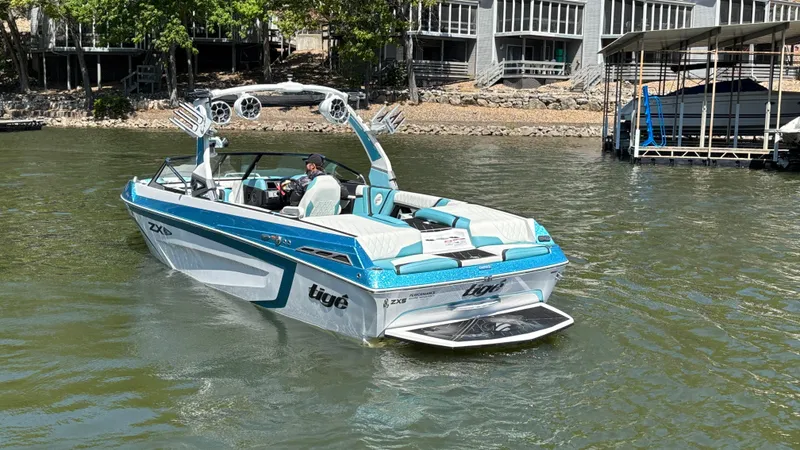Slide: The Image of 2019 Tigé 25 ZXS boat on a lake near docks and trees. - 7
