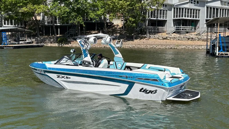 Slide: The Image of 2019 Tigé 25 ZXS boat on a lake near docks and trees. - 9