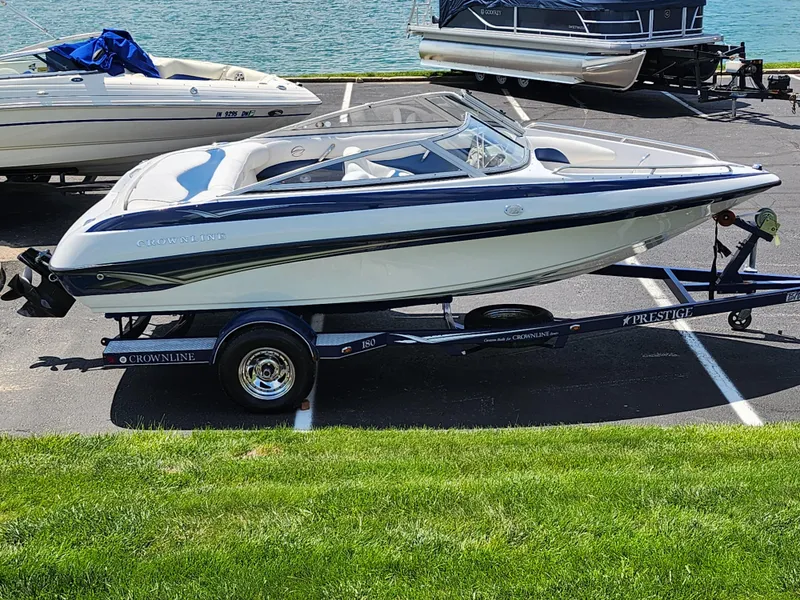 Slide: The Image of 2008 Crownline 180 BR boat on trailer by waterfront, parked on asphalt. - 0
