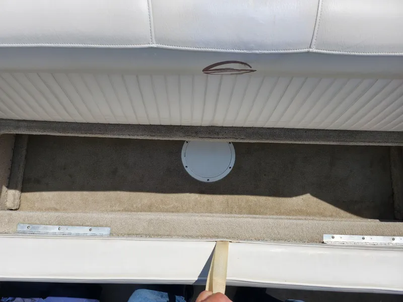 Slide: The Image of Crownline 180 BR 2008 boat interior storage compartment with beige carpet and white upholstery. - 24