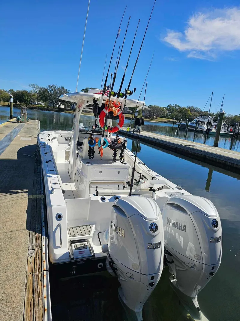 Slide: The Image of 2025 Tidewater 272 CC Adventure boat docked with dual Yamaha engines and fishing rods. - 3