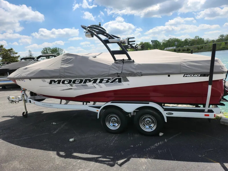 Slide: The Image of 2013 Moomba Mojo 2.5 boat on trailer, covered, parked outdoors under a cloudy sky. - 11
