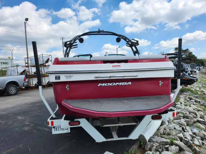 Slide: The Image of 2013 Moomba Mojo 2.5 boat, red and white, parked outdoors under a cloudy sky. - 2