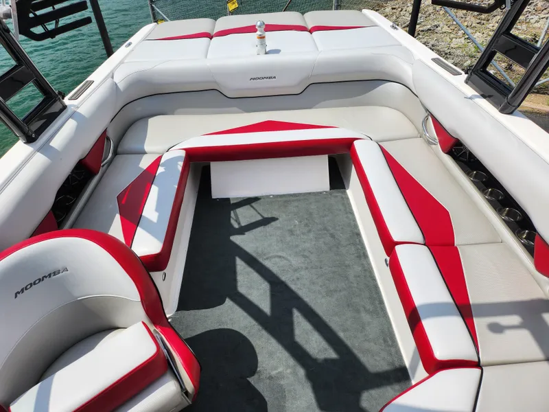 Slide: The Image of 2013 Moomba Mojo 2.5 boat interior with red and white seating, docked by the water. - 25
