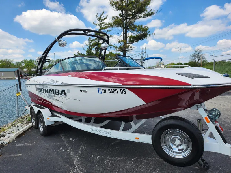 Slide: The Image of 2013 Moomba Mojo 2.5 boat on trailer, red and white, parked near water. - 6