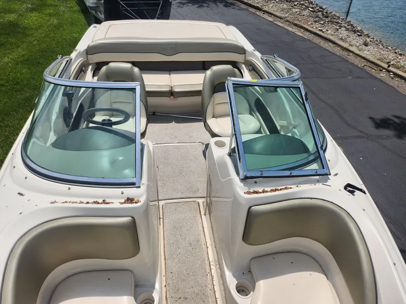 Slide: The Image of 2004 Sea Ray 200 Sport boat interior with open windshield, beige seating, and steering wheel. - 19