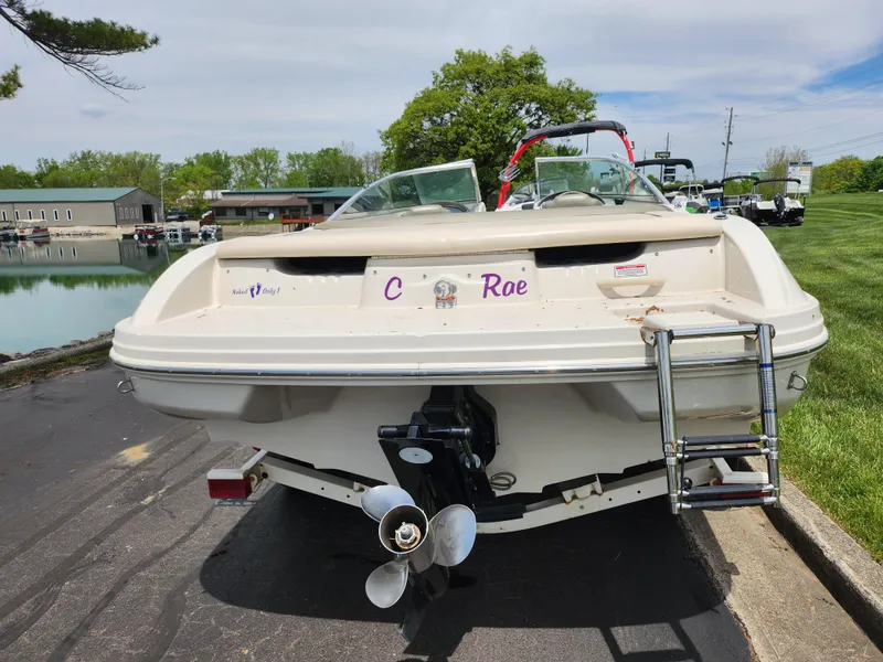 Slide: The Image of 2004 Sea Ray 200 Sport boat with ladder, parked near a marina. - 2