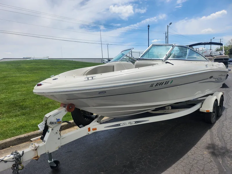 Slide: The Image of 2004 Sea Ray 200 Sport boat on trailer, parked outdoors under a partly cloudy sky. - 4