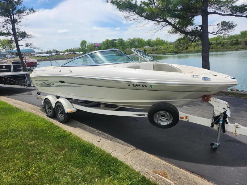 Slide: The Image of 2004 Sea Ray 200 Sport boat on trailer by a lakeside road. - 8