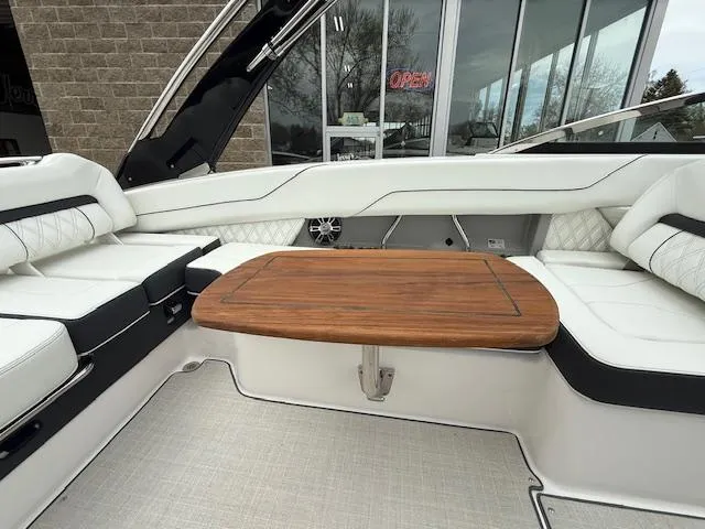Slide: The Image of 2023 Regal LS6 boat interior with white seating and wooden table. - 32