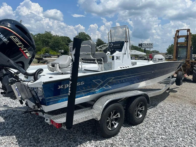 Slide: The Image of 2025 Xpress H22 Bay boat on trailer, parked outdoors under cloudy sky. - 2