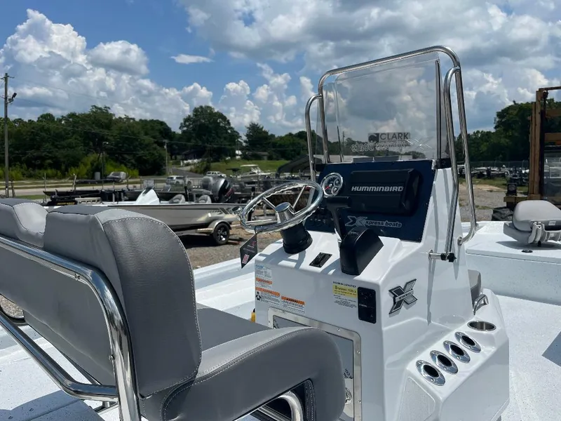 Slide: The Image of 2025 Xpress H22 Bay boat with steering console and seating, under a partly cloudy sky. - 5