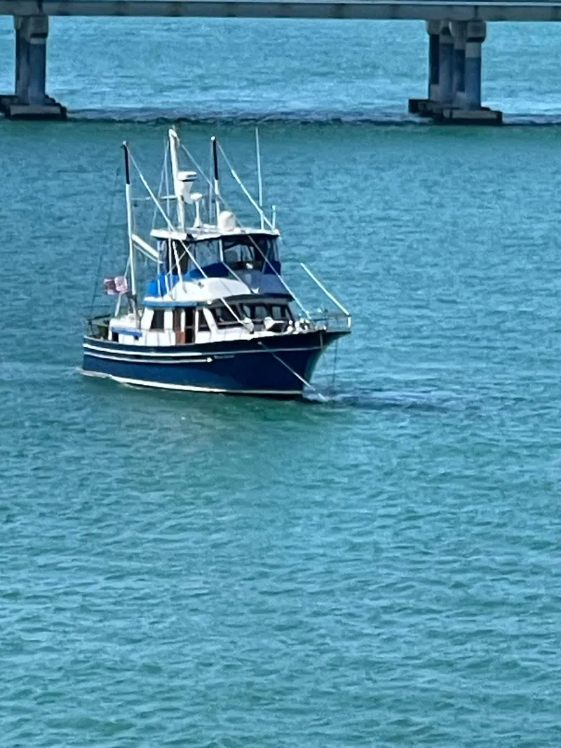 Slide: The Image of 1981 Albin 45 Command Bridge cruising under a bridge on calm blue waters. - 25