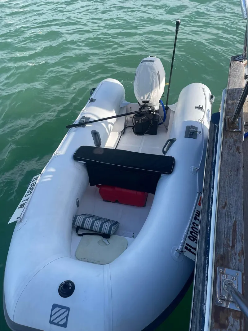 Slide: The Image of Inflatable boat docked beside Albin 45 Command Bridge, 1981 model, on calm water. - 43