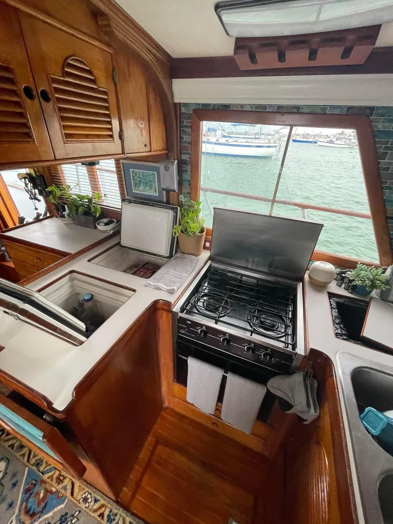 Slide: The Image of 1981 Albin 45 Command Bridge kitchen with stove, sink, and waterfront view. - 48