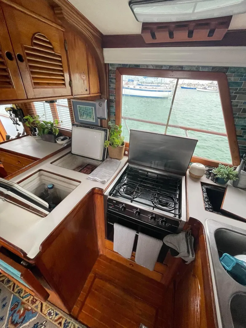 Slide: The Image of 1981 Albin 45 Command Bridge kitchen with stove, sink, and waterfront view. - 49