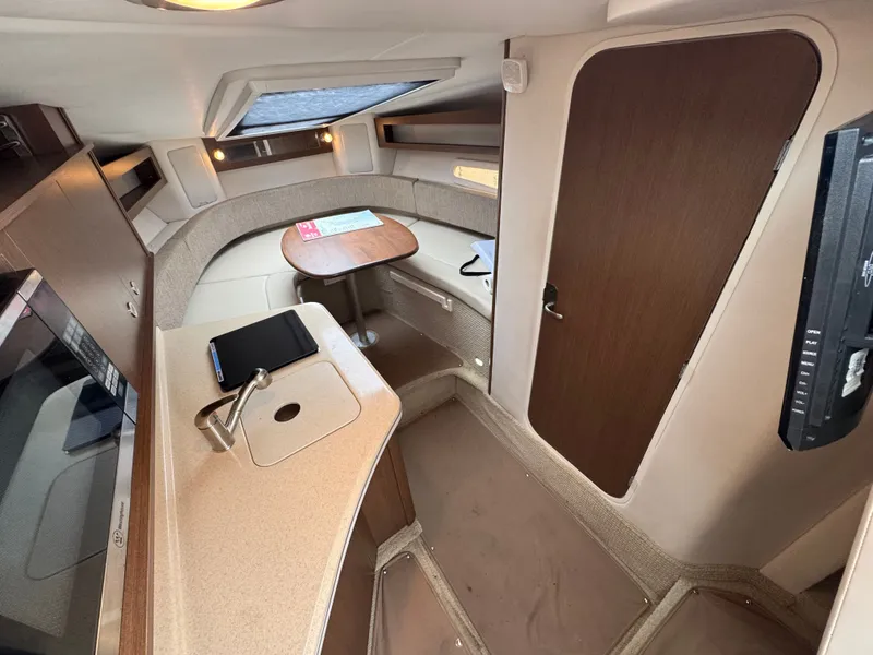 Slide: The Image of Interior of 2015 Sea Ray 280 Sundancer with kitchenette, seating, and wooden accents. - 42