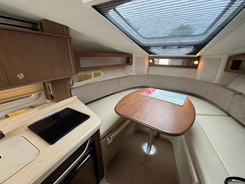 Slide: The Image of 2015 Sea Ray 280 Sundancer cabin interior with table, seating, and skylight. - 49