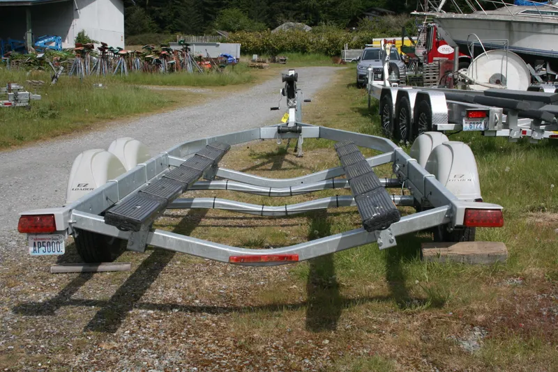 Slide: The Image of 2023 Hewescraft 210 Sea Runner ET HT boat trailer on gravel path, surrounded by greenery. - 15