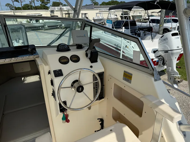 Slide: The Image of 2004 Parker 2510 Walkaround boat cockpit with steering wheel and navigation instruments. - 16