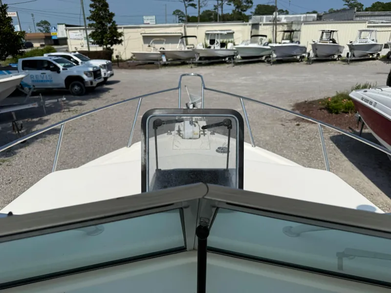 Slide: The Image of 2004 Parker 2510 Walkaround boat in a dealership lot, surrounded by other boats and vehicles. - 24