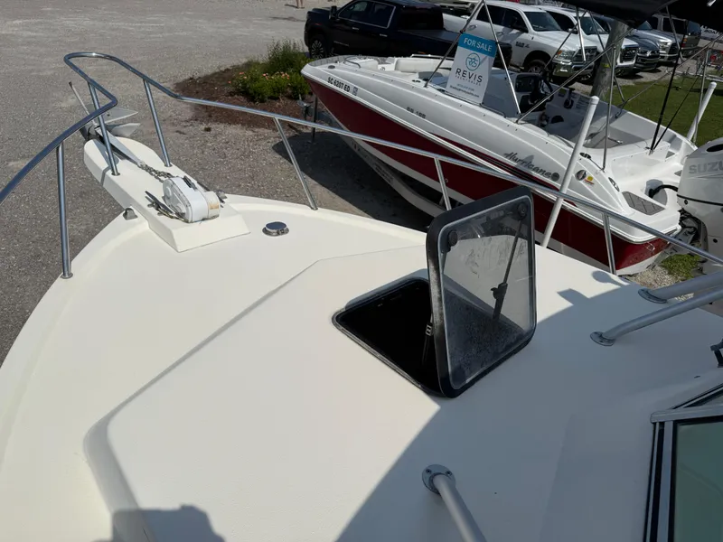 Slide: The Image of 2004 Parker 2510 Walkaround boat deck with open hatch, parked near other boats. - 25