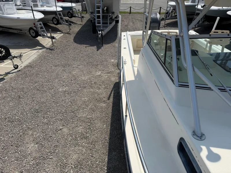 Slide: The Image of 2004 Parker 2510 Walkaround boat on gravel lot, surrounded by trailers and other boats. - 29