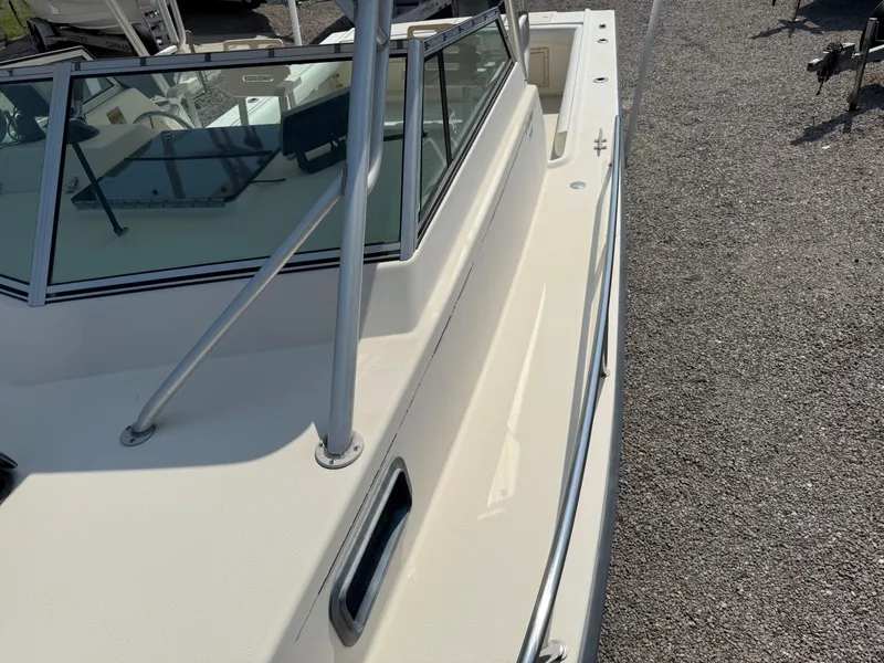 Slide: The Image of 2004 Parker 2510 Walkaround boat deck with windshield and railing, on gravel surface. - 30
