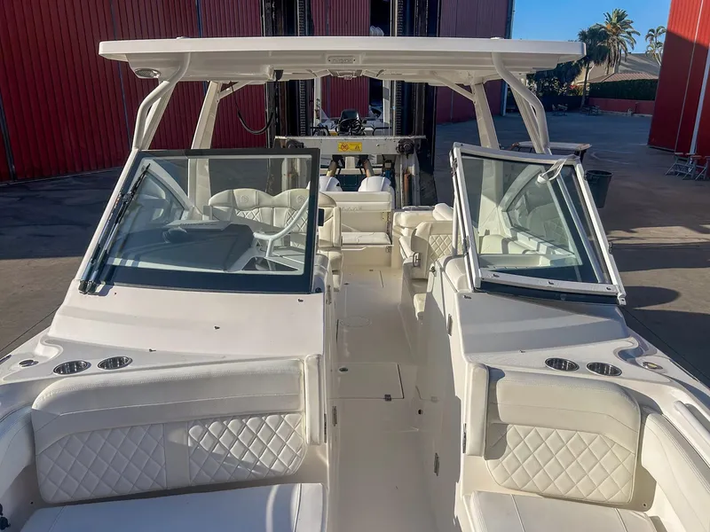 Slide: The Image of 2020 Edgewater 262 CX boat with open cockpit and seating, docked near red building. - 12