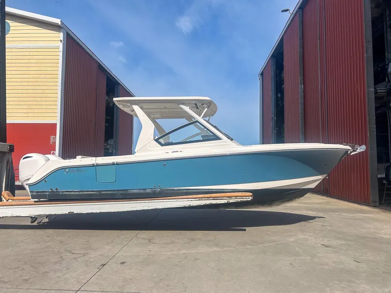 Slide: The Image of 2020 Edgewater 262 CX boat in storage facility, blue and white design. - 2