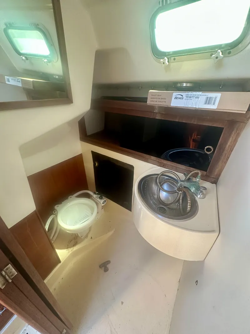 Slide: The Image of 1979 O'Day Center Cockpit bathroom with sink, toilet, and storage shelves. - 29