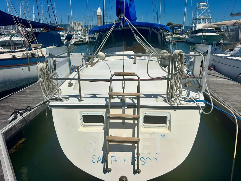 Slide: The Image of 1979 O'Day Center Cockpit sailboat docked in a marina, rear view with ladder and ropes. - 8