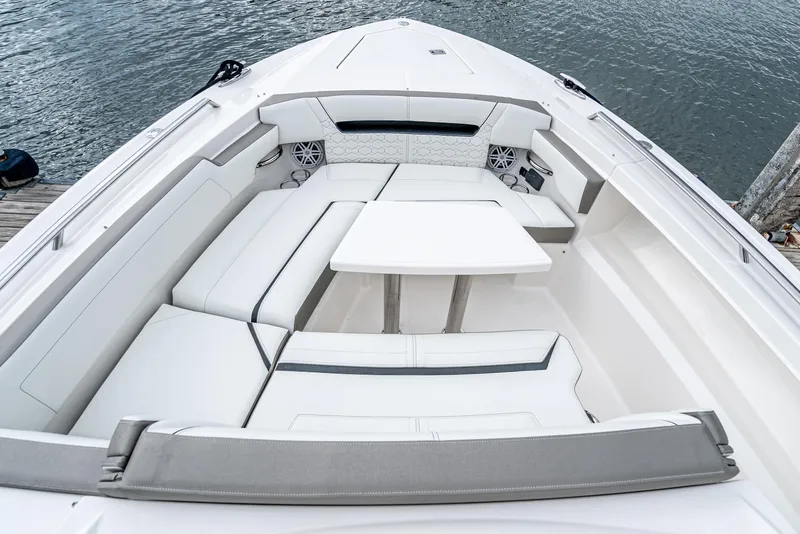 Slide: The Image of 2024 Tiara Yachts 34 LS boat interior with white seating and table, docked by water. - 10