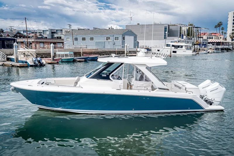 Slide: The Image of 2024 Tiara Yachts 34 LS in marina, sleek design, blue hull, modern coastal setting. - 4