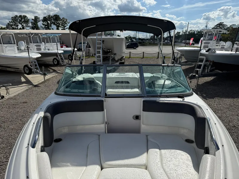 Slide: The Image of 2015 Chaparral 21 H2O Sport boat with seating, windshield, and canopy in a marina setting. - 9