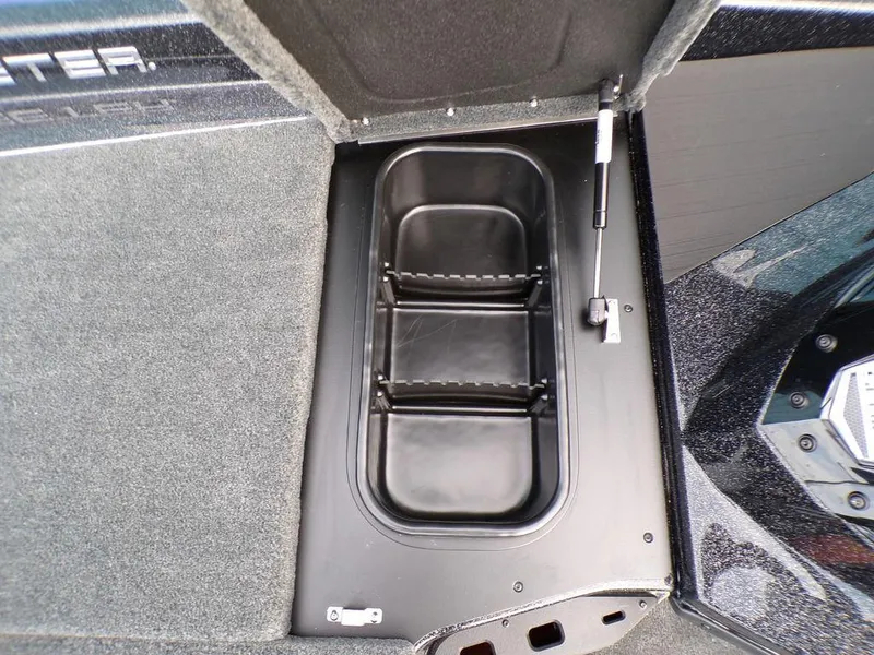Slide: The Image of 2025 Skeeter ZXR20 boat storage compartment with black interior and carpeted surroundings. - 15